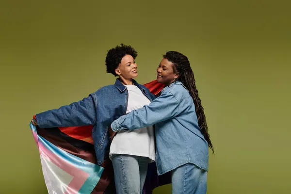 Two beautiful women celebrate their love, wrapped in a colorful flag, radiating joy and style. — Fotografia de Stock