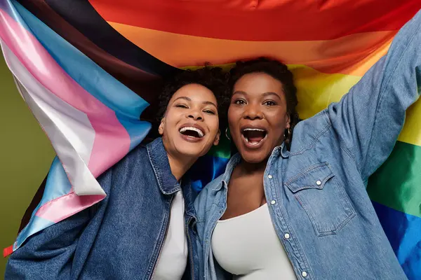 Duas mulheres na moda expressam seu amor e alegria enquanto ostentam orgulhosamente bandeiras vibrantes. — Fotografia de Stock