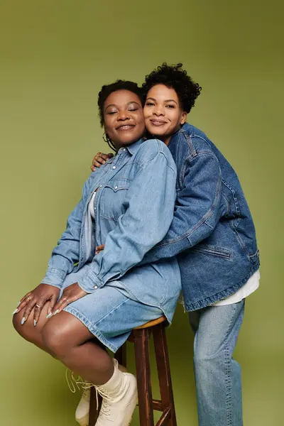 Deux belles femmes en tenues denim tendance partagent un moment d'amour plein de joie et de style. — Photo de stock