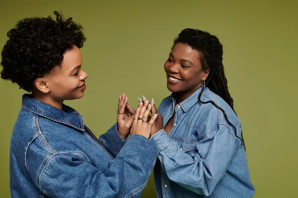 Two stylish women share a joyful moment in trendy denim jackets, reflecting their bond. — Stock Photo