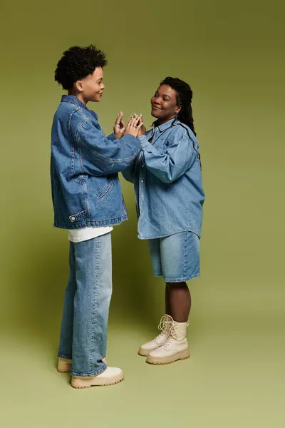 Two fashionable women in stylish denim embrace, radiating love and happiness in a bright setting. — Stock Photo