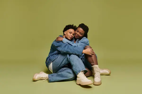 In a bright green backdrop, a loving lesbian couple shares a tender moment in fashionable denim. — Stock Photo