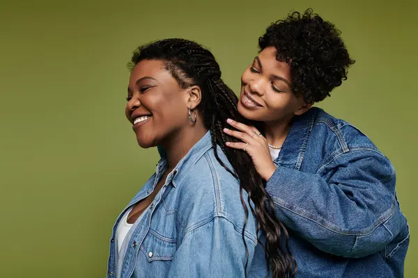 A beautiful couple enjoys a tender moment while dressed in chic denim outfits on a bright backdrop. — Stock Photo