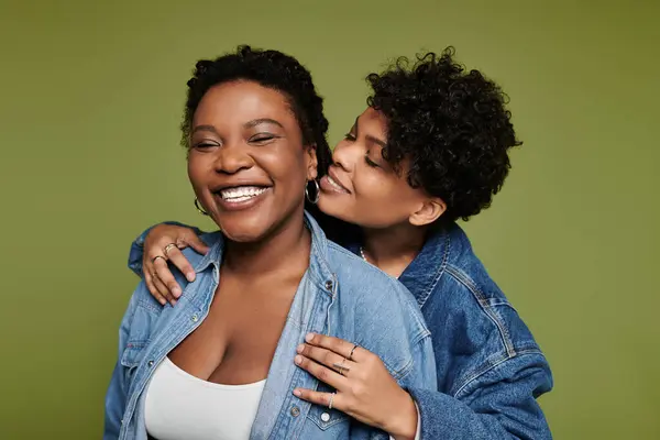 Two fashionable women embrace happily, showcasing their love and connection in vivid hues. — Stock Photo