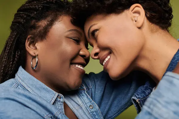 Two stylish women joyfully embrace in front of a vibrant backdrop. — Stock Photo