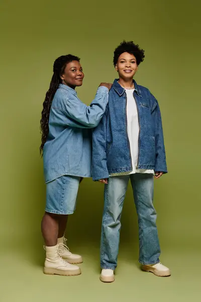 Two stylish individuals share their love in trendy denim against a vibrant backdrop. — Stock Photo
