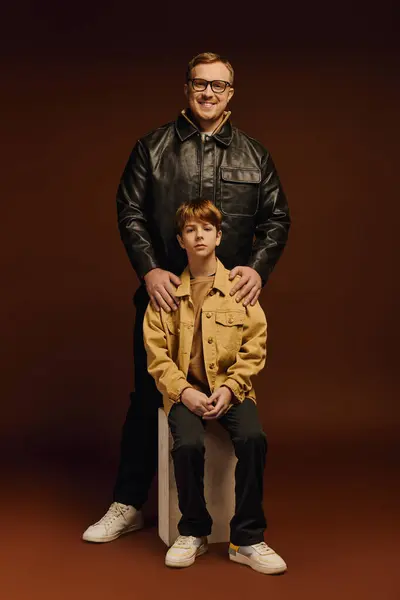 Father and son share a joyful moment, showcasing their stylish casual looks in a studio. — Stock Photo