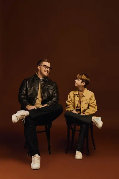 A happy father and son share a lighthearted moment in a studio, dressed in trendy casual wear. — Stock Photo