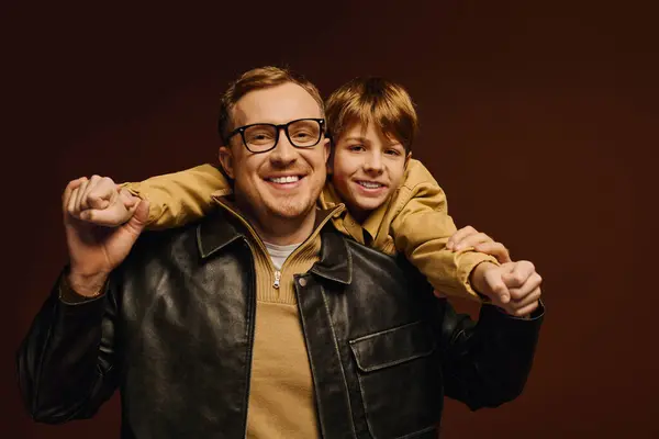 Joyful father and son share a playful moment in a warm-toned studio, showcasing their love. — Stock Photo