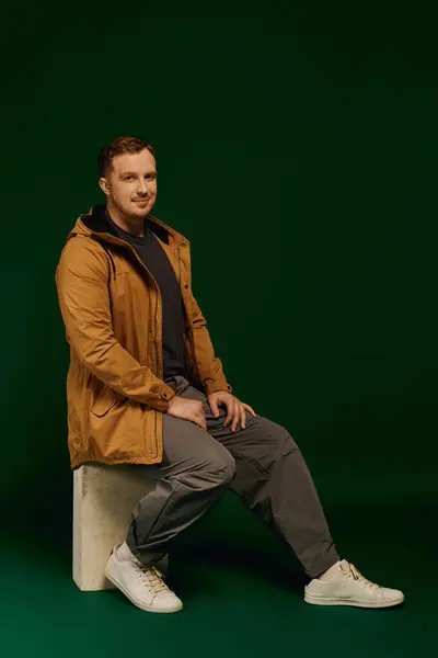 Стильний чоловік сидить розслабленим на блоці, демонструючи модний повсякденний одяг у студійній обстановці. — Stock Photo