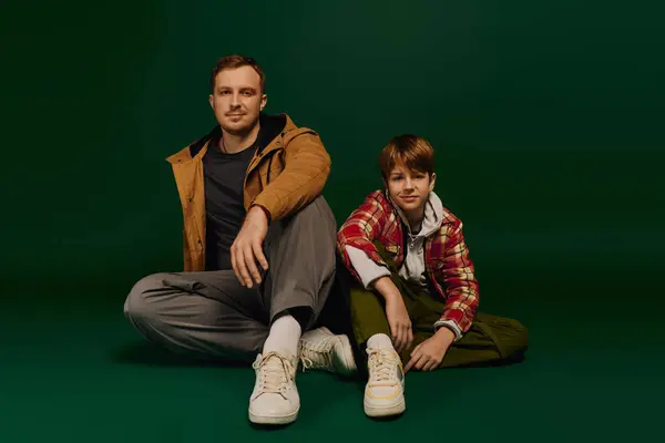 Father and son pose together in a studio, sharing happy smiles and showcasing their casual fashion. — Stock Photo