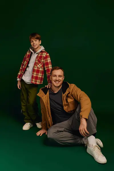 Father and son radiate happiness, showcasing their casual outfits in a cheerful studio atmosphere. — Stock Photo