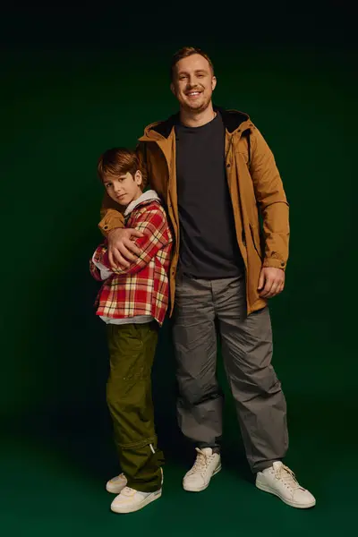 Father and son showcase their cheerful bond while wearing casual outfits in a studio. — Stock Photo
