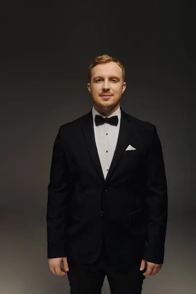 A handsome man in a tailored tuxedo exudes confidence and charm in a studio. — Stock Photo