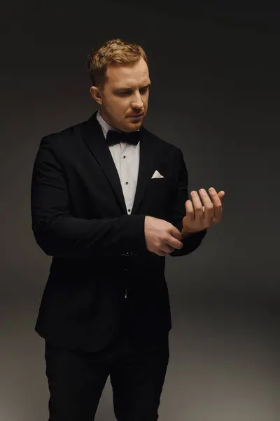 A dapper gentleman fine-tunes his cufflinks while dressed in an elegant tuxedo, exuding charm. — Stock Photo