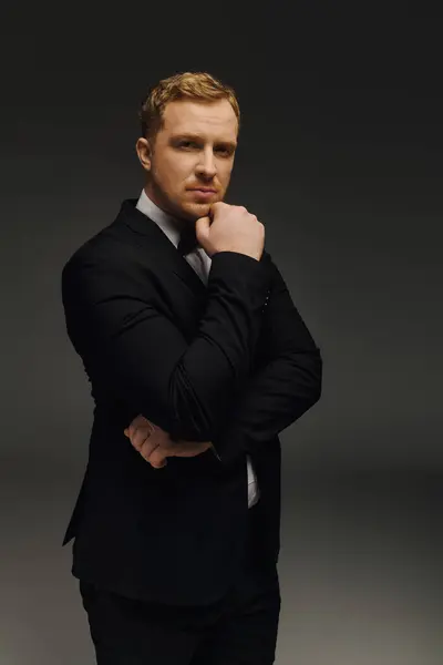 Ein gut gekleideter Mann steht in nachdenklicher Pose in einem modernen Studio-Ambiente und versprüht Charme. — Stockfoto