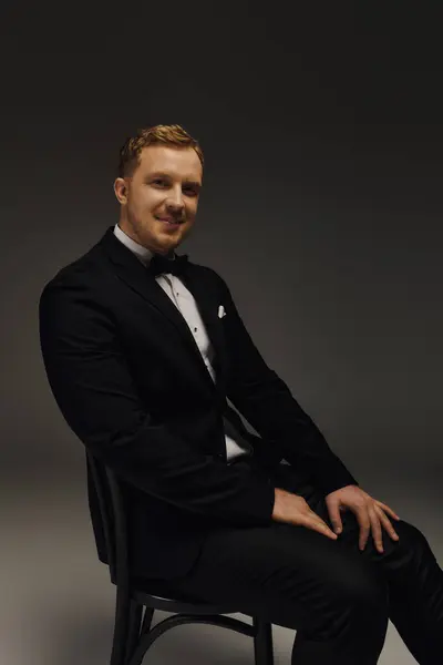 A handsome man dressed in a classic tuxedo and bow tie poses confidently, showcasing elegance. — Stock Photo