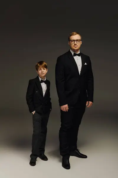 Father and son stand confidently in stylish tuxedos, highlighting their elegant bond in a studio. — Stock Photo
