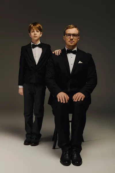 Father and son stand proudly in matching tuxedos, showcasing their stylish bow ties. — Stock Photo
