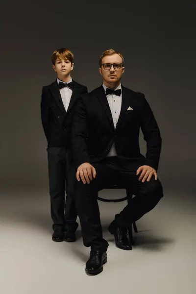Father and son showcase their style in a tailored tuxedo and bow ties while posing elegantly. — Stock Photo