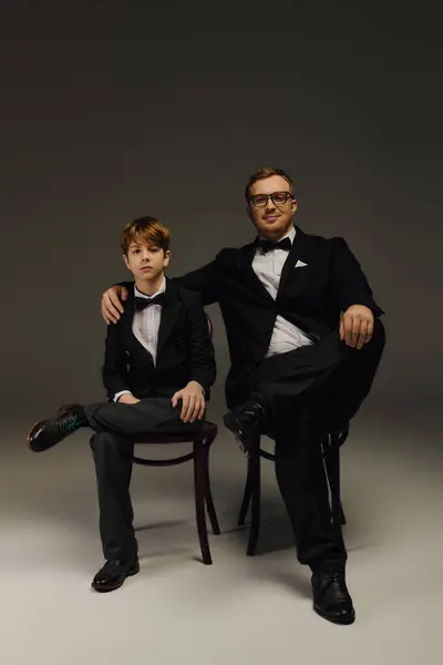 Father and son bond in elegant tuxedos, exuding confidence and style in the studio. — Stock Photo