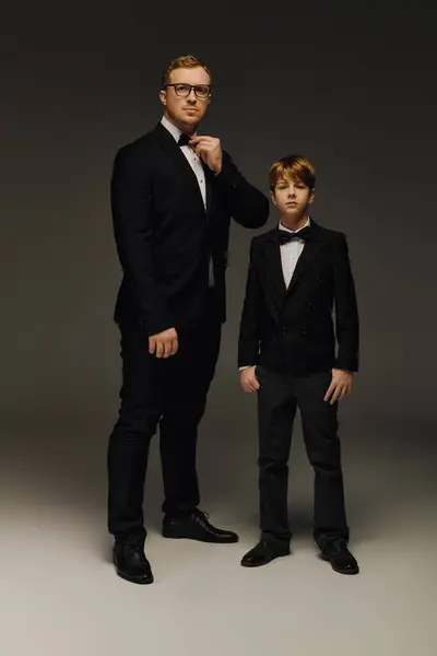 Dressed to impress, a handsome father and his son pose together in elegant tuxedos. — Stock Photo