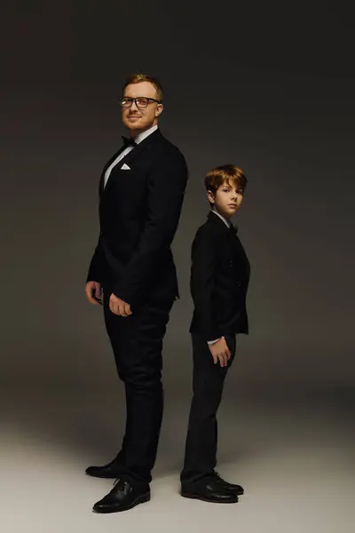 Handsome father and son stand tall in a studio, showcasing their elegance in tuxedos. — Stock Photo