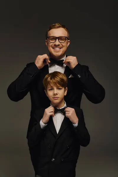 A handsome father and son pose together in tuxedos, exuding charm and elegance in a studio. — Stock Photo