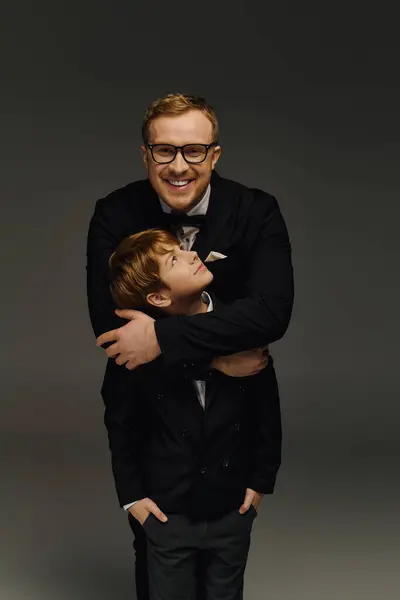 Dressed in elegant tuxedos, a father and son showcase their stylish bond while posing cheerfully. — Stock Photo