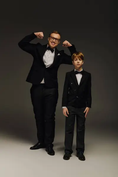 Dressed in tuxedos, a proud father and son pose together in an elegant studio setting with charm. — Stock Photo