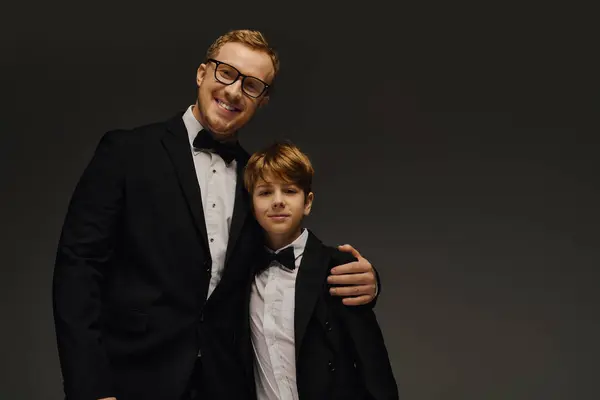 A proud father and his young son display their charm in elegant tuxedos, embracing warmly. — Stock Photo