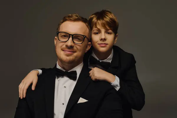 Father and son look sharp in tuxedos, capturing a timeless bond in a stylish studio. — Stock Photo