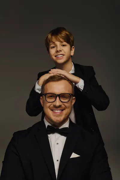 Father and son pose together, showcasing their stylish suits in a professional studio setting. — Stock Photo