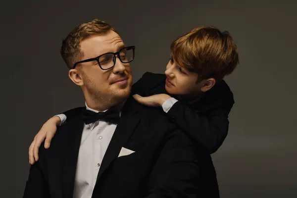 A father and son enjoy a touching moment while dressed in elegant tuxedos, showcasing their bond. — Stock Photo