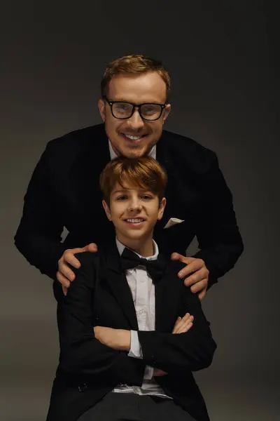 Handsome father and son dressed in classic tuxedos exude charm and sophistication in studio. — Stock Photo