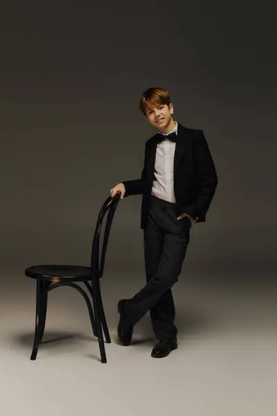 Dressed in a smart tuxedo with a bow tie, a preteen boy poses confidently in a studio. — Stock Photo