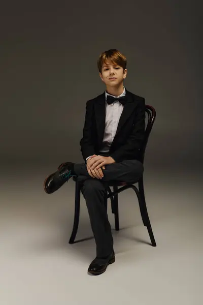 A young boy in a classic suit and bow tie poses elegantly in a studio — Stock Photo