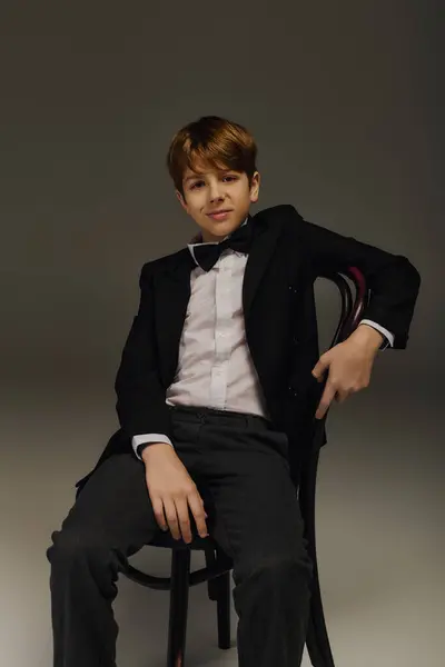 A preteen boy dressed in a tuxedo with a bow tie poses confidently in a studio environment. — Stock Photo