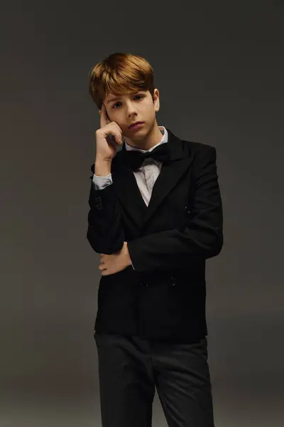 A preteen boy dressed in a sharp suit and bow tie strikes a confident pose in a studio. — Stock Photo