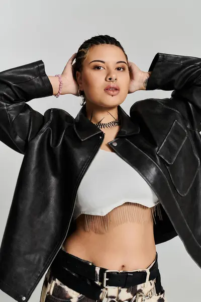 A stylish young woman poses confidently in a studio, showcasing her trendy outfit. — Stock Photo