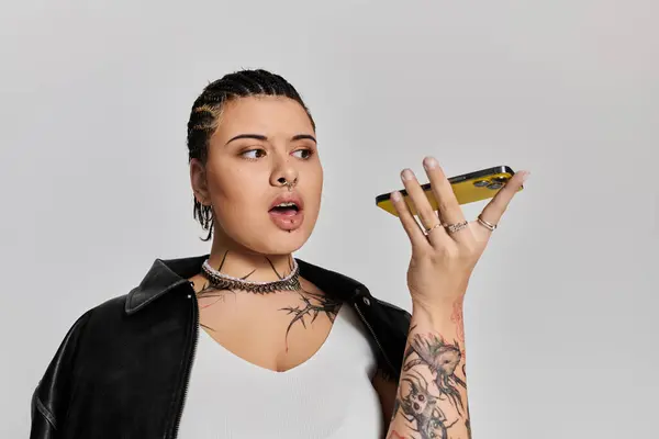 Stylish woman with intricate tattoos holds her phone thoughtfully while expressing herself. — Stock Photo