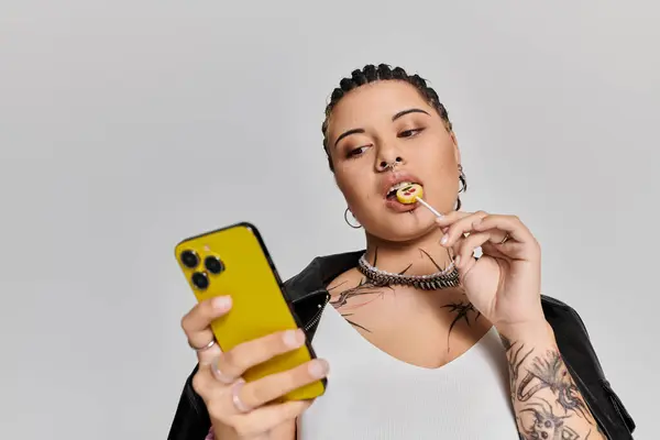 Une jeune femme élégante aime les bonbons tout en se concentrant sur son smartphone. — Photo de stock