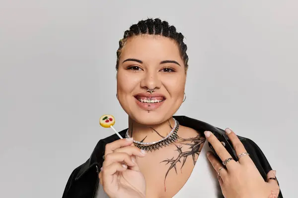 Eine junge und modische Frau lächelt strahlend, während sie einen Lutscher in der Hand hält und ihren einzigartigen Stil präsentiert. — Stockfoto