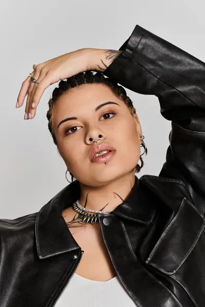 Jeune femme pose avec confiance dans une veste en cuir chic, embrassant un style urbain à la mode. — Photo de stock