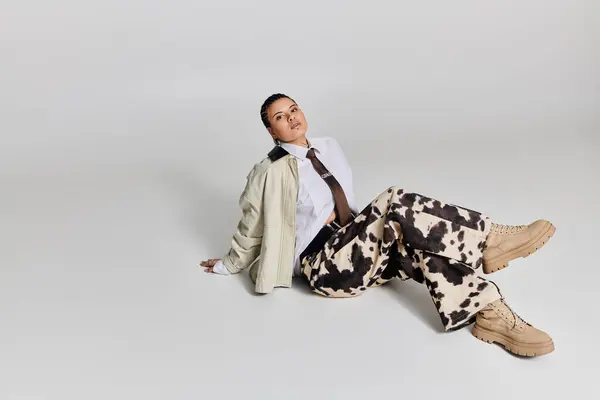 Junge Frau zeigt ihren einzigartigen Sinn für Mode, während sie in einem Atelier auf dem Boden sitzt. — Stockfoto