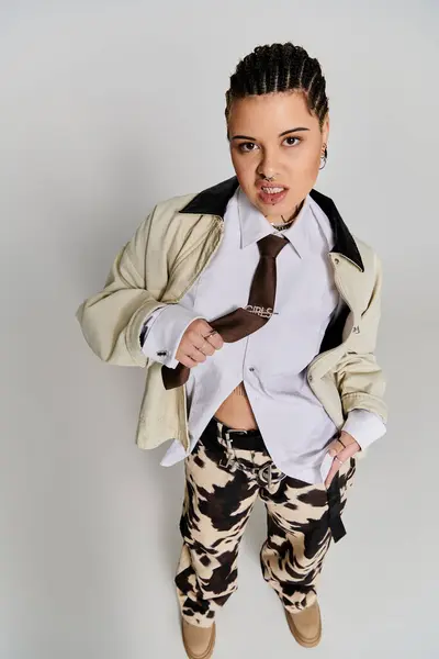 Une jeune femme se tient hardiment dans une tenue élégante sur fond neutre. — Photo de stock