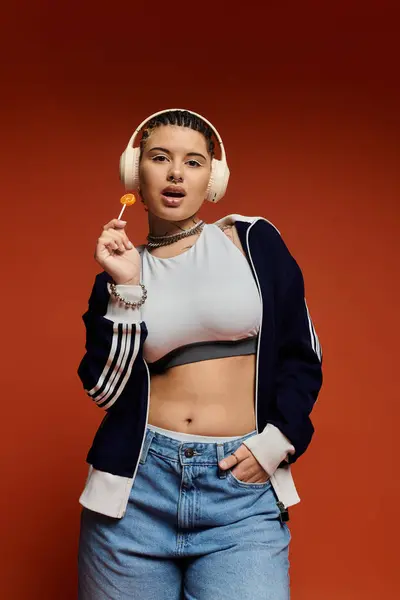 Une jeune femme élégante pose en toute confiance, profitant d'une sucette et exhibant sa mode. — Photo de stock