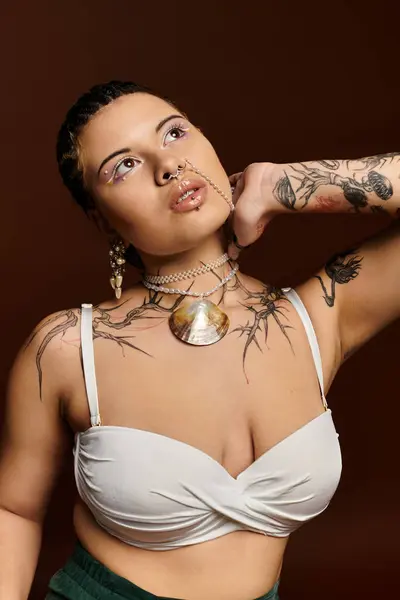 Une jeune femme élégante affiche ses tatouages audacieux et des bijoux frappants dans un espace confortable. — Photo de stock