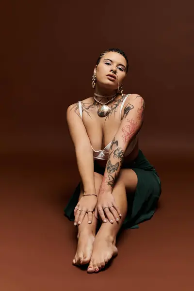 Confident woman poses stylishly, showcasing her artistic tattoos against a warm backdrop. — Stock Photo