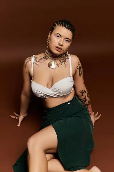 Jovem mostra seu olhar elegante com tatuagens, jóias e confiança em um estúdio vibrante. — Fotografia de Stock